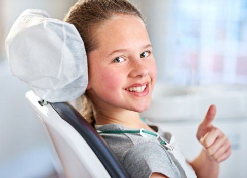Child giving thumbs up after sedation dentistry for kids.