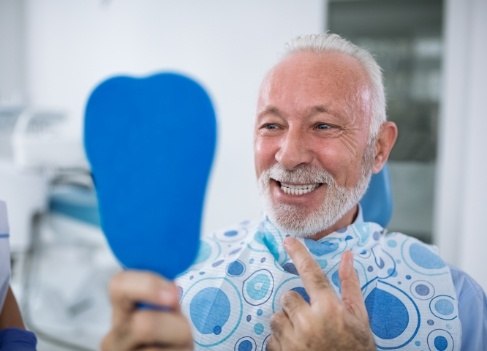 Man looking at smile in mirror after dental checkup and teeth cleaning