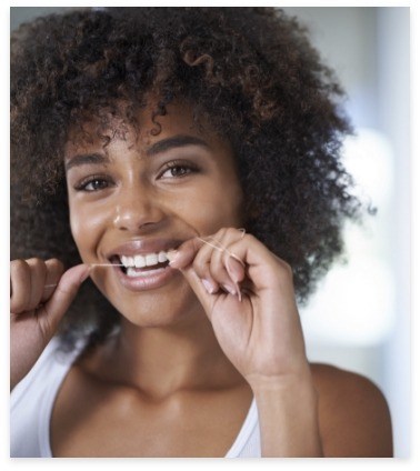 Woman flossing teeth after preventive dentistry visit