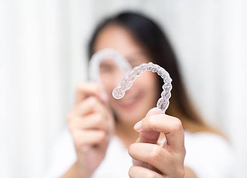 Smiling patient holding clear aligners