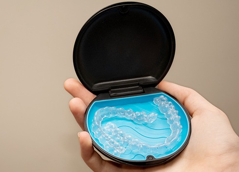 Patient holding clear aligners in black and blue case