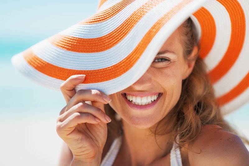A smiling woman wearing a beach hat