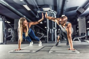 Man and woman high-fiving on yoga mats at the gym